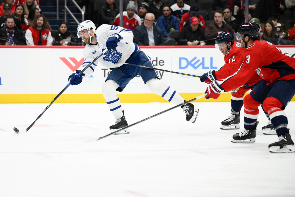 Toronto Maple Leafs center Nicolas Roy, left, shoots the puck past Washington Capitals left wing Anthony Beauvillier, second from right, and defenseman Matt Roy (3) during the second period of an NHL hockey game, Thursday, Dec. 18, 2025, in Washington. (AP Photo/Nick Wass)