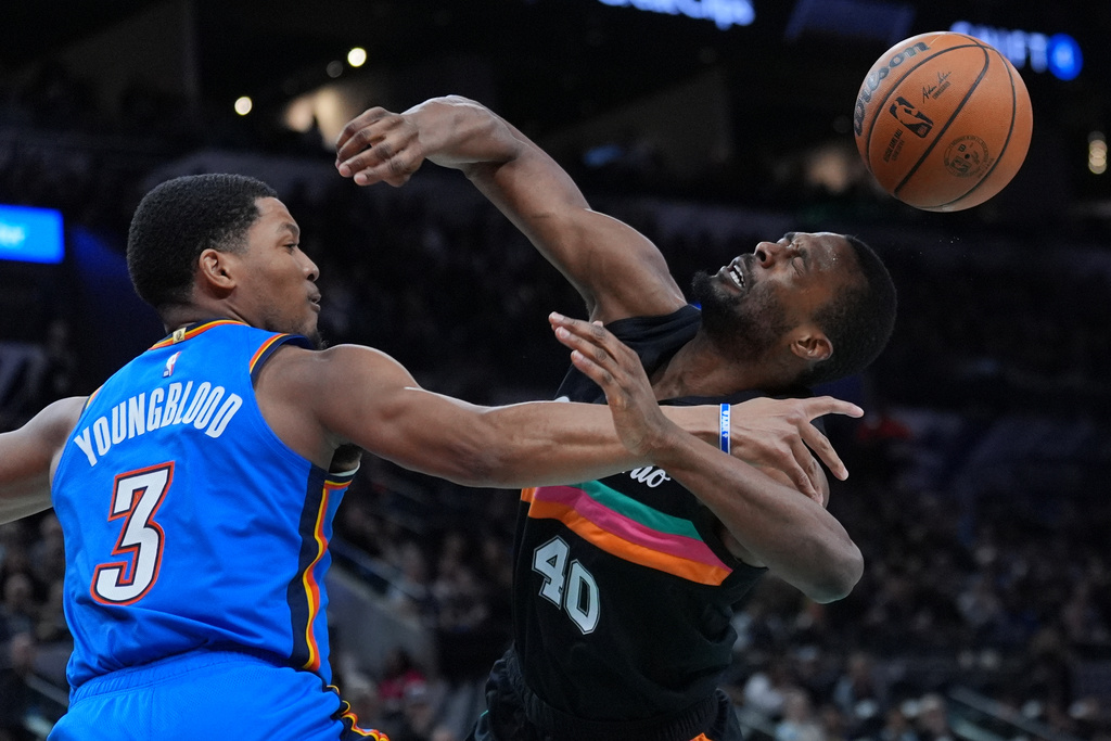 San Antonio Spurs forward Harrison Barnes (40) is fouled by Oklahoma City Thunder guard Chris Youngblood (3) as he drives to the basket during the second half of an NBA basketball game in San Antonio, Wednesday, February. 4, 2026. (AP Photo/Eric Gay)