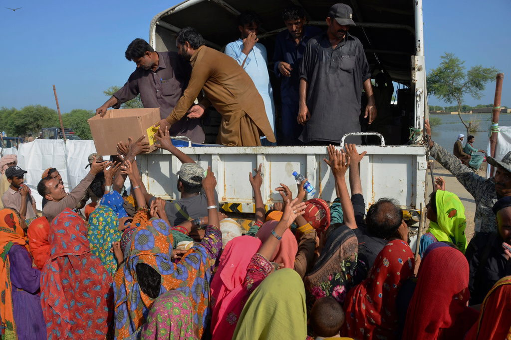 FILE - Displaced families, who fled their flood-hit homes, jostle to get relief aid distributed by soldiers of Pakistan rangers, in Dera Allahyar, in Jaffarabad, a district of southwestern Balochistan province, Sept. 17, 2022. (AP Photo/Zahid Hussain, File)