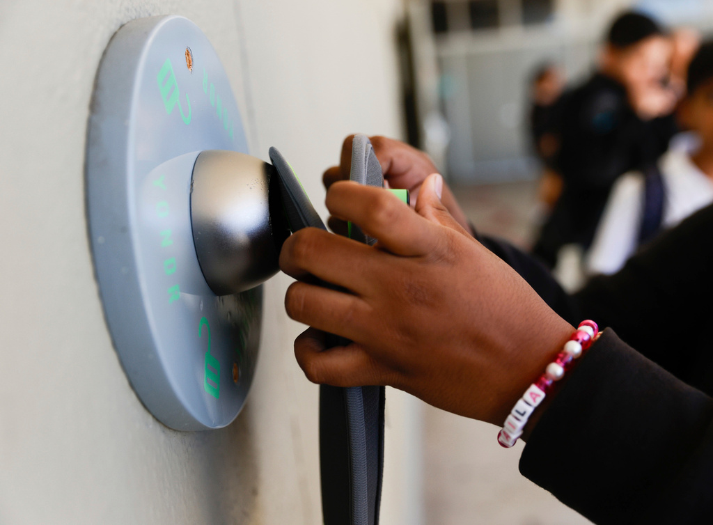FILE - A middle school student unlocks a Yondr pouch on an unlocking base at Bayside Academy while others wait in line for their turn to unlock their pouch at the end of the school day Aug. 16, 2024, in San Mateo, Calif. (Lea Suzuki/San Francisco Chronicle via AP, File)