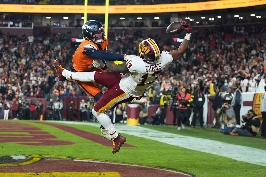 Washington Commanders wide receiver Treylon Burks (13) catches a touchdown pass as Denver Broncos cornerback Riley Moss, left, defends during the second half of an NFL football game Sunday, Nov. 30, 2025, in Landover, Md. (AP Photo/Stephanie Scarbrough)