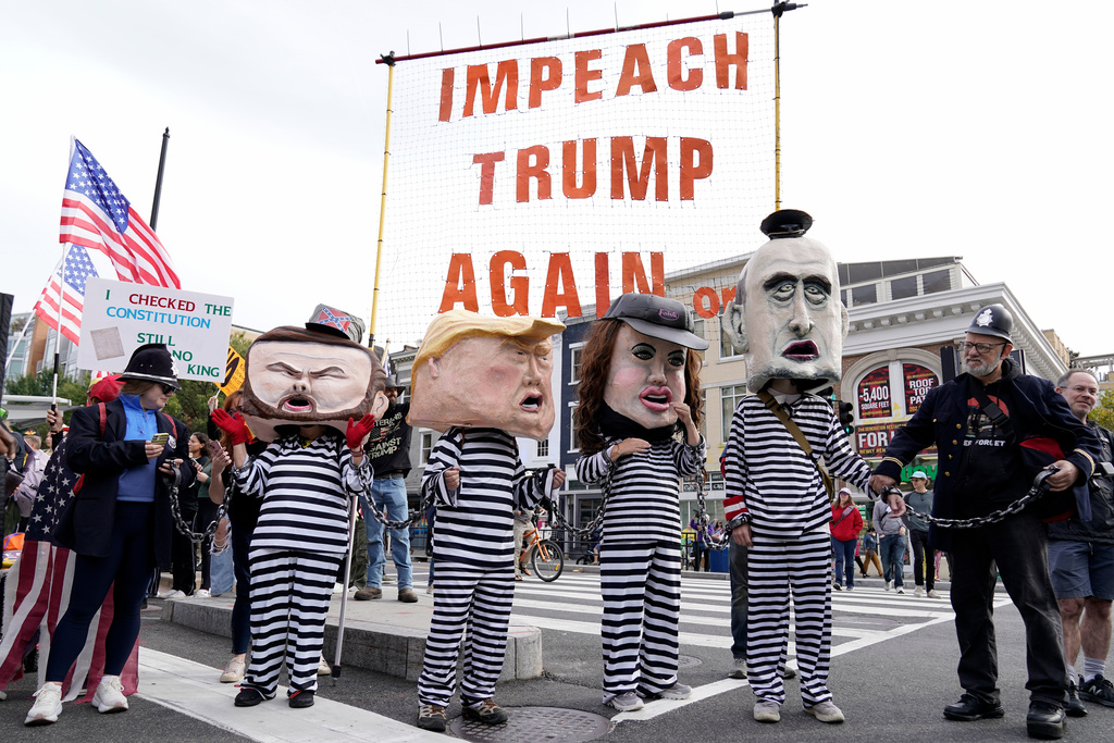 Demonstrators wear costumes and carry signs as they rally at the 14th and U street corridor before marching to the national Mall during a No Kings protest in Washington, Saturday, Oct. 18, 2025. (AP Photo/Jose Luis Magana)