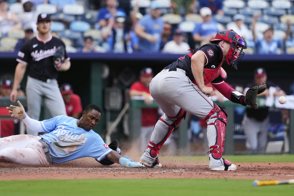 Kansas City Royals' Tyler Tolbert (2) beats the tag by Washington Nationals catcher Riley Adams to score the game-tying run on a sacrifice fly hit by Bobby Witt Jr. during the eighth inning of a baseball game Wednesday, Aug. 13, 2025, in Kansas City, Mo. (AP Photo/Charlie Riedel)