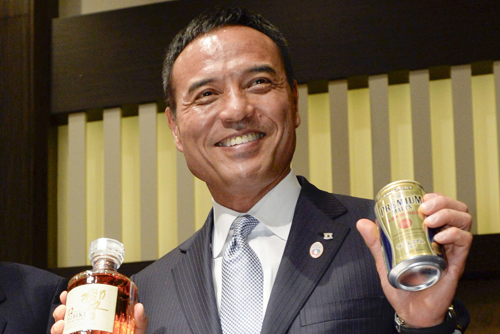 Takeshi Niinami, then new president of Japan’s major beverage maker Suntory holds the beverage maker’s products after a press conference on July 1, 2014 in Tokyo. (Kyodo News via AP)
