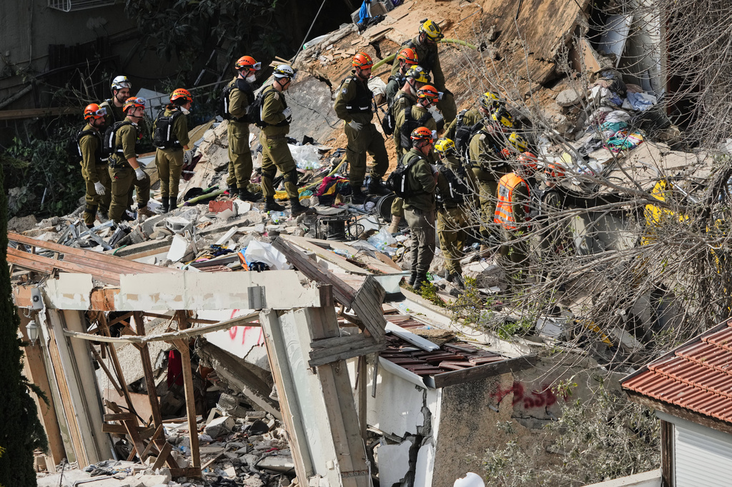 Israeli rescue teams search for missing people amid the rubble of a residential building a day after it was struck by an Iranian missile in Haifa, Israel, Monday, April 6, 2026. (AP Photo/Ariel Schalit)
