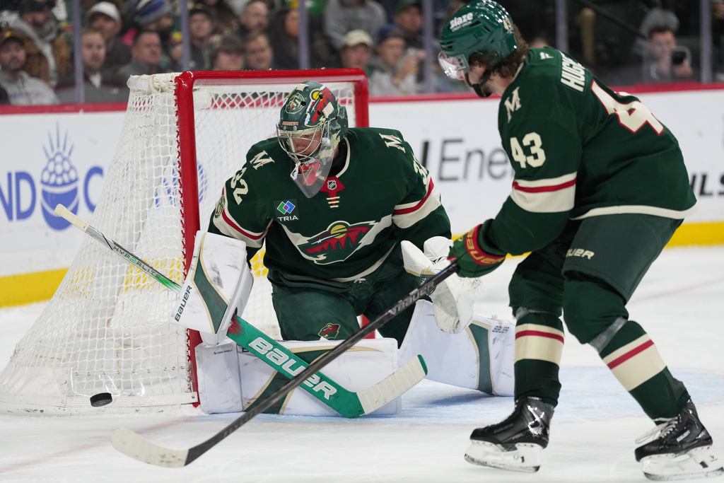 Minnesota Wild goaltender Filip Gustavsson (32) and defenseman Quinn Hughes (43) defend during the second period of an NHL hockey game against the Calgary Flames, Thursday, Jan. 29, 2026, in St. Paul, Minn. (AP Photo/Abbie Parr)
