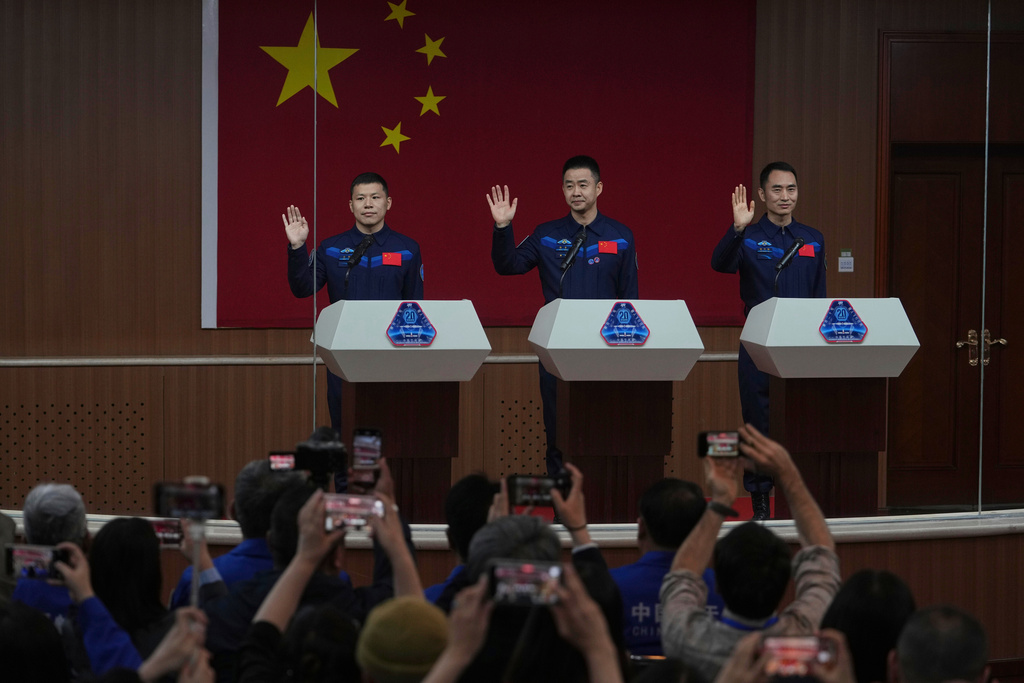 FILE - Journalists film Chinese astronauts for the upcoming Shenzhou 20 mission, from left, Wang Jie, captain Chen Dong and Chen Zhongrui wave at the Jiuquan Satellite Launch Center in northwest China, Wednesday, April 23, 2025. (AP Photo/Andy Wong, file)