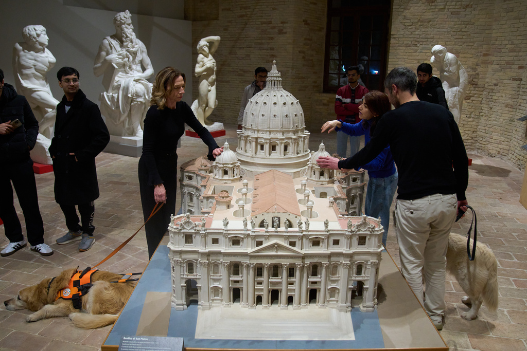 Stefania Terre, left, and Carmine Laezza, far right, both blind, touch a reproduction of St. Peter's Basilica at the Omero Tactile Museum in Ancona, Italy, Thursday, Jan. 15, 2026. (AP Photo/Alessandra Tarantino)