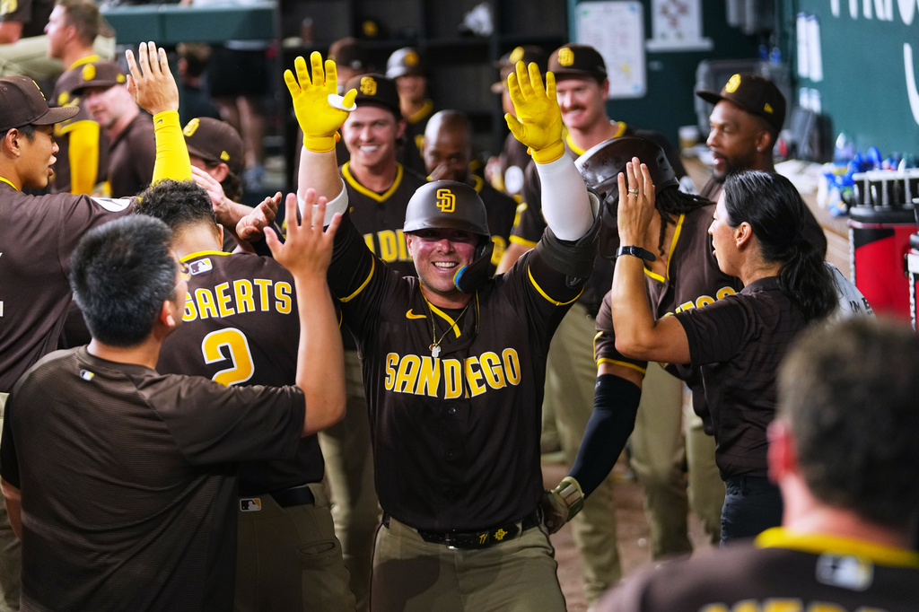 San Diego Padres' Ty France is greeted in the dugout after hitting a solo home run off Texas Rangers starting pitcher Jacob Degrom during the fourth inning of a baseball game, Friday, June 19, 2026 in Arlington, Texas. (AP Photo/Julio Cortez)