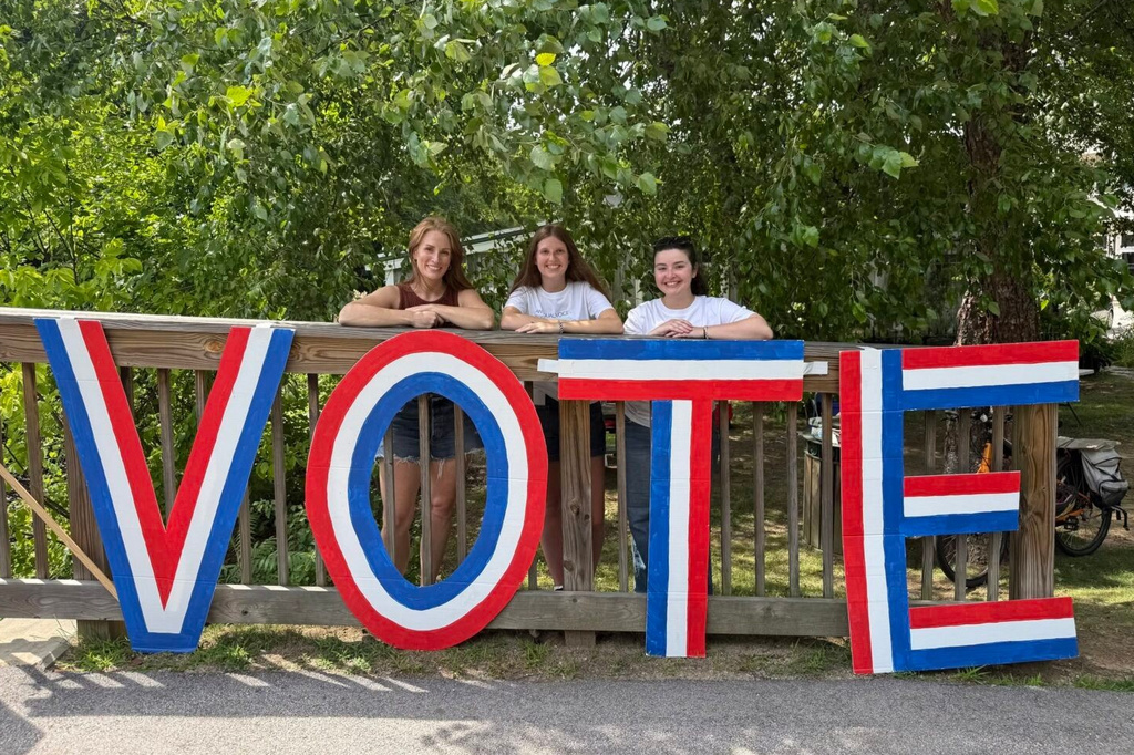 From left, Coalition for Open Democracy's Voter Education Coordinator Sarah Ortiz, summer student Intern Emma Repici, and Development and Communications Coordinator Kaylie Efstratiou pose behind a large VOTE sign on Aug. 1, 2026, in Peterborough, N.H. (Sam Cassin/InDepthNH.org via AP)