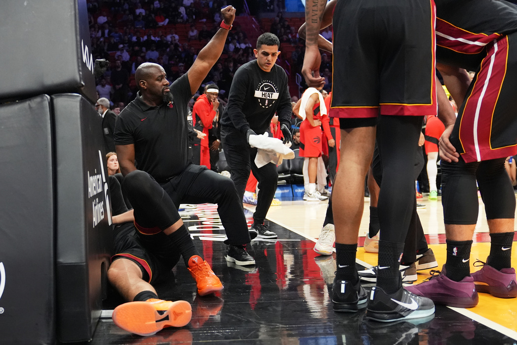 A Member of the Miami Heat coaching staff gestures as forward Nikola Jovic, left, lies on the court during the first half of an NBA basketball game against the Toronto Raptors, Monday, Dec. 15, 2025, in Miami. (AP Photo/Lynne Sladky)