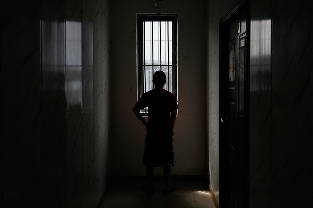 A rescued Chinese scam worker who said he was beaten multiple times and is now serving in the witness protection program for the Philippines authorities and using the pseudonym Jade, looks out a window at the Presidential Anti-Organized Crime Commission temporary detention center, a former scam compound, in Pasay, Philippines Thursday, June 5, 2025. (AP Photo/Aaron Favila)