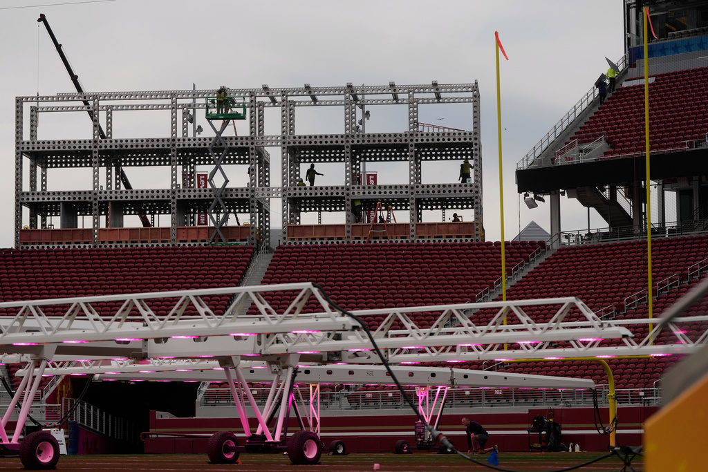 Workers build a structure above grow lights on the field at Levi's Stadium as it is prepared for the NFL's Super Bowl LX football game in Santa Clara, Calif., Tuesday, Jan. 20, 2026. (AP Photo/Jeff Chiu)