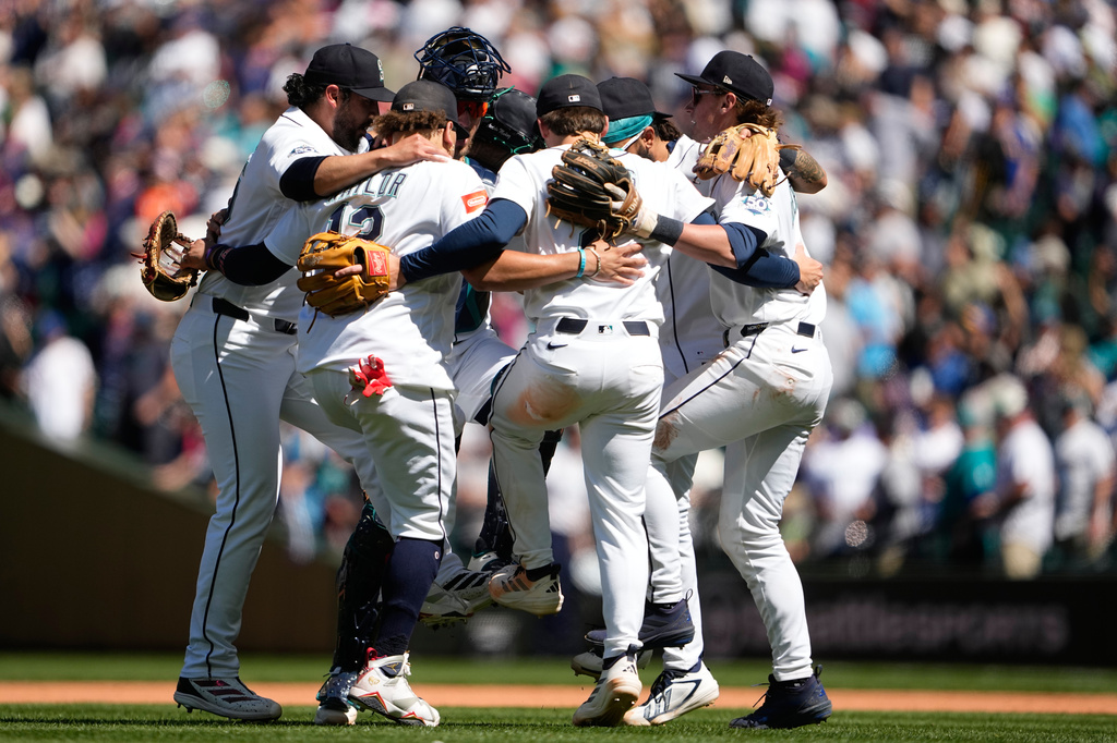 The Seattle Mariners infield, including relief pitcher Andrés Muñoz, far left, first baseman Josh Naylor (12), second baseman Cole Young and shortstop Colt Emerson, right, celebrate a win over the Baltimore Orioles after a baseball game, Thursday, June 18, 2026, in Seattle. (AP Photo/Lindsey Wasson)
