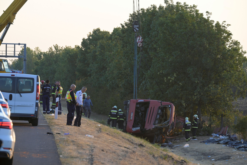 Emergency services attend the scene after a passenger bus went off the road and overturned in a ditch along a highway between Mezokeresztes and Mezonagymihaly in Hungary, Sunday, Aug. 16, 2026. (Zoltan Mathe/MTI via AP)
