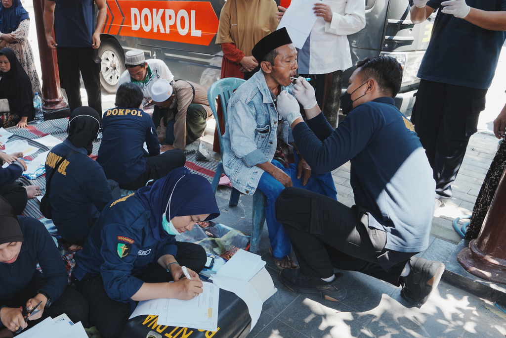 Members of police forensic unit collect DNA sample from students' family members after a building under construction collapsed Monday at an Islamic boarding school in Sidoarjo, East Java, Indonesia, Thursday, Oct. 2, 2025. (AP Photo/Achmad Ibrahim)