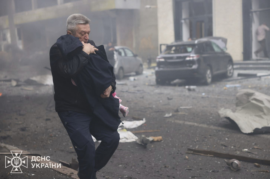 In this photo provided by the Ukrainian Emergency Service, a man evacuates a child after Russian drones hit a city kindergarten in Kharkiv, Ukraine, Wednesday, Oct. 22, 2025. (Ukrainian Emergency Service via AP)