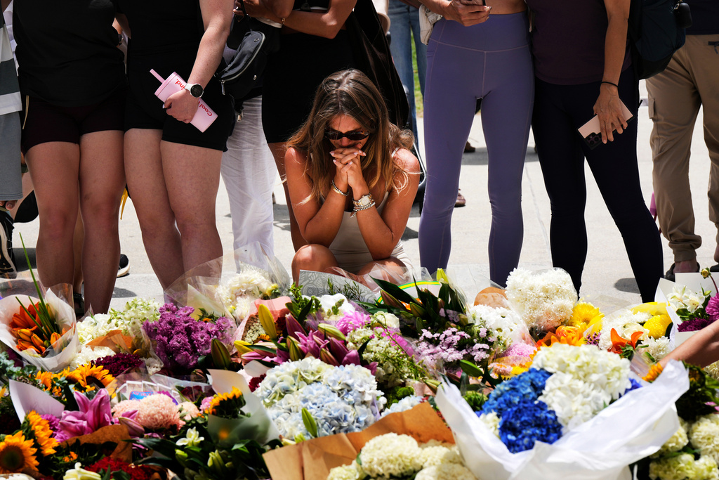 A woman kneels and prays at a flower memorial to shooting victims outside the Bondi Pavilion at Sydney's Bondi Beach, Monday, Dec. 15, 2025, a day after a shooting. (AP Photo/Mark Baker)