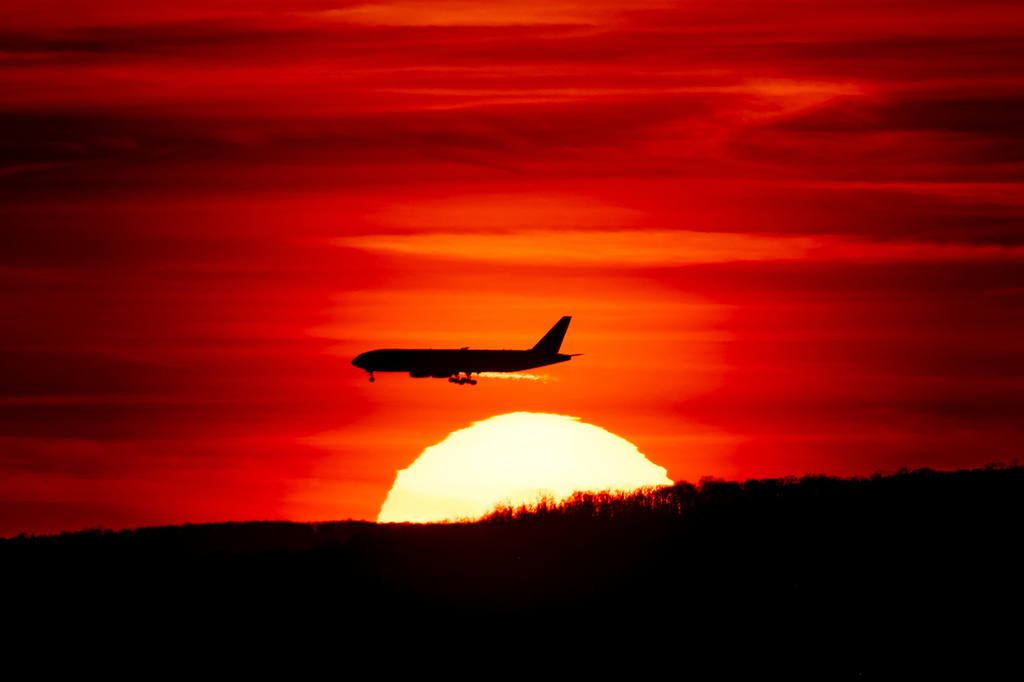 FILE - A passenger jet on approach to Newark Liberty International Airport flies over the setting sun in Newark, N.J., March 27, 2019. (AP Photo/J. David Ake, File)