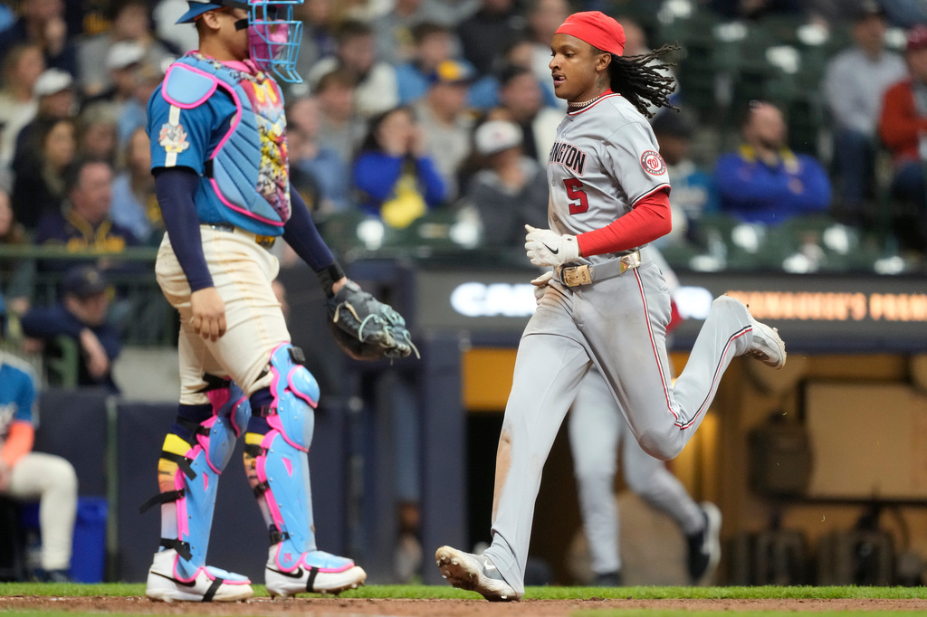 Washington Nationals' CJ Abrams (5) scores on an RBI single hit by Luis García Jr. as Milwaukee Brewers catcher William Contreras, left, looks on during the ninth inning of a baseball game, Friday, April 10, 2026, in Milwaukee. (AP Photo/Kayla Wolf)
