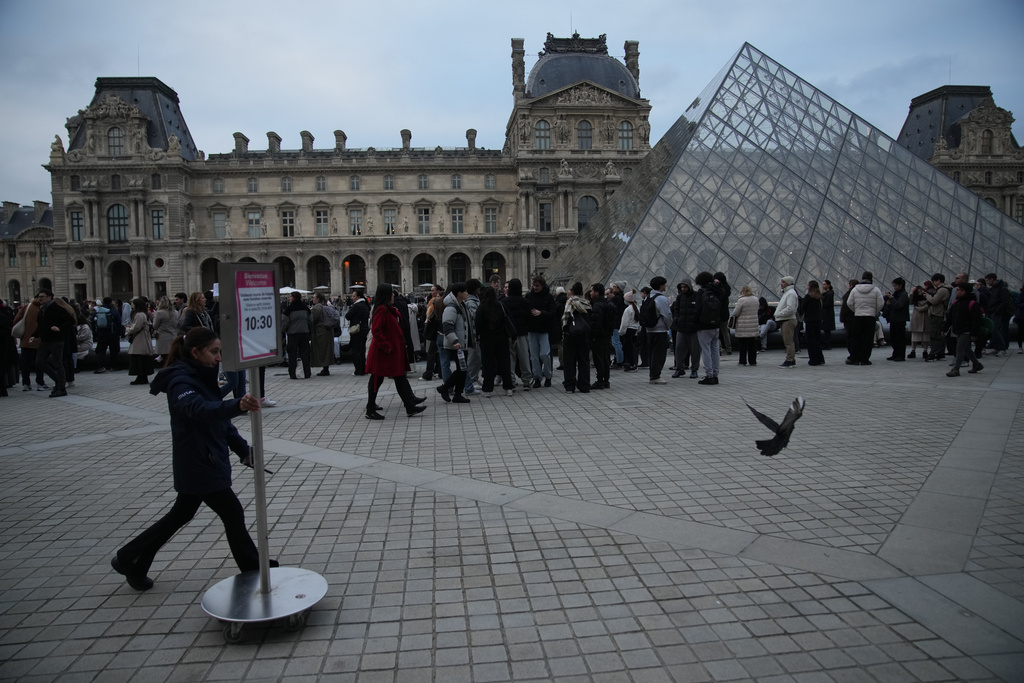 People wait at the entrance of the Louvre museum as employees were set to vote on whether to extend a strike that shut the world's most visited museum, as unions protest chronic understaffing, building deterioration and recent management decisions Wednesday, Dec. 17, 2025 in Paris. (AP Photo/Christophe Ena)