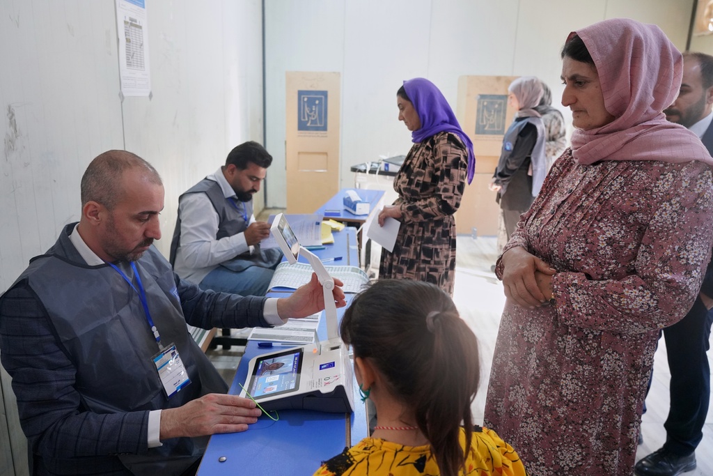 Displaced Yazidi women have their fingerprints verified before voting ahead of Iraq's parliamentary elections, set for Nov. 11, at a polling station in the Sharia camp near Dohuk, in Iraq's semi-autonomous Kurdish region, Sunday, Nov. 9, 2025. (AP Photo/Rashid Yahya)