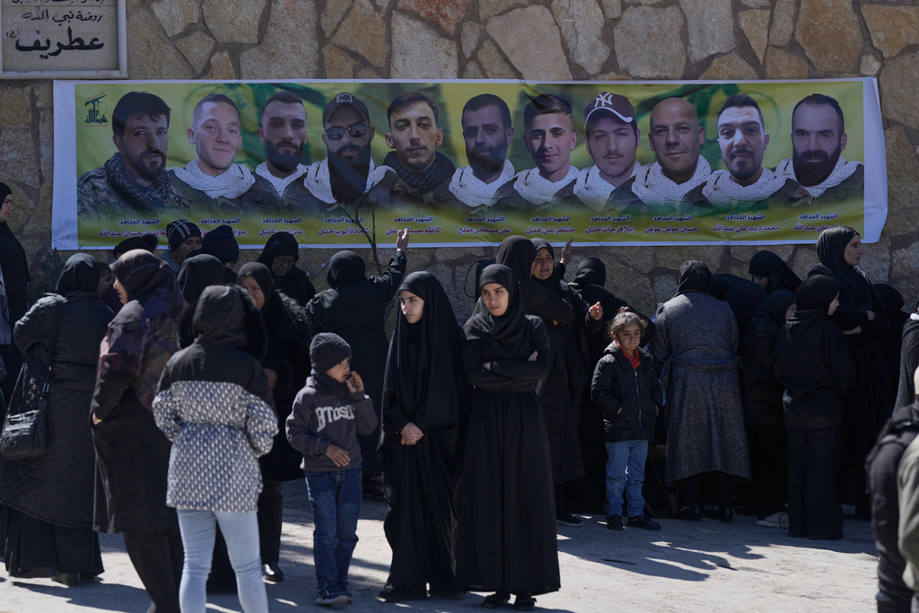Mourners gather in frontof the portraits of Hezbollah fighters who were killed by Israeli airstrikes during their funeral procession in Khreibeh village, eastern Lebanon, Sunday, March 8, 2026. (AP Photo/Bilal Hussein)