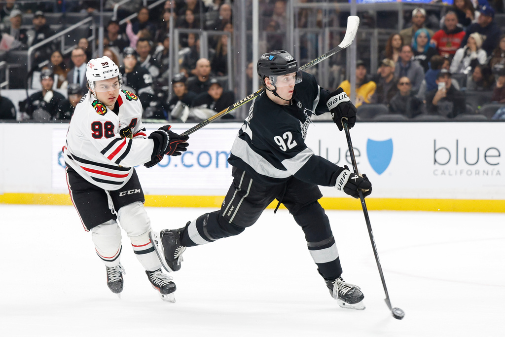 Los Angeles Kings defenseman Brandt Clarke (92) takes a shot and scores as Chicago Blackhawks center Connor Bedard (98) trails behind during the second period of an NHL hockey game Saturday, Dec. 6, 2025, in Los Angeles. (AP Photo/Caroline Brehman)