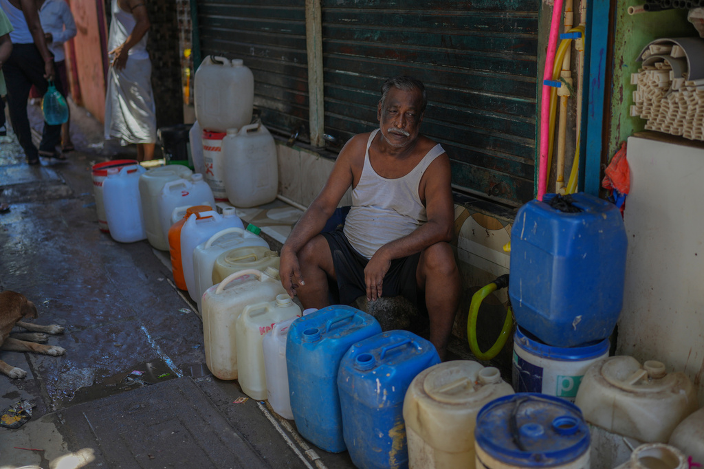 A slum resident waits to collect water in a narrow lane of a slum settlement in Mumbai, India, Sunday, June 21, 2026. (AP Photo/Rafiq Maqbool)