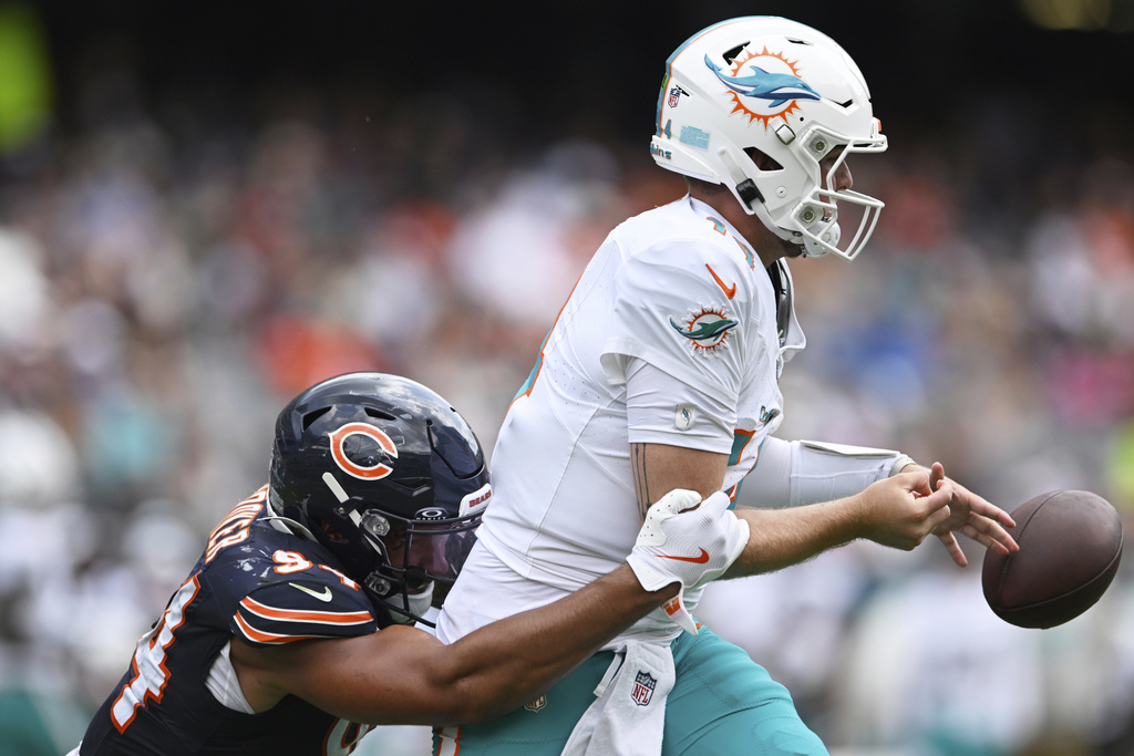 Chicago Bears defensive end Austin Booker, left, sacks Miami Dolphins quarterback Quinn Ewers, right, causing a fumble during the second half of an NFL preseason football game, Sunday, Aug. 10, 2025, in Chicago. (AP Photo/Paul Beaty)