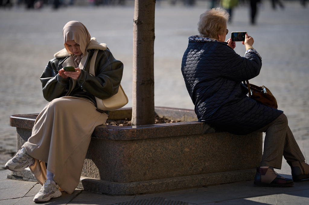 Women hold their cellphones in Red Square, in Moscow, Wednesday, March 11, 2026. (AP Photo/Alexander Zemlianichenko)