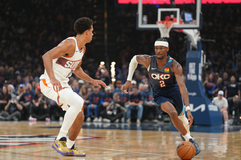Oklahoma City Thunder guard Shai Gilgeous-Alexander, right, drives past Phoenix Suns forward Oso Ighodaro during the second half in Game 2 of a first-round NBA playoffs basketball series Wednesday, April 22, 2026, in Oklahoma City. (AP Photo/Kyle Phillips)