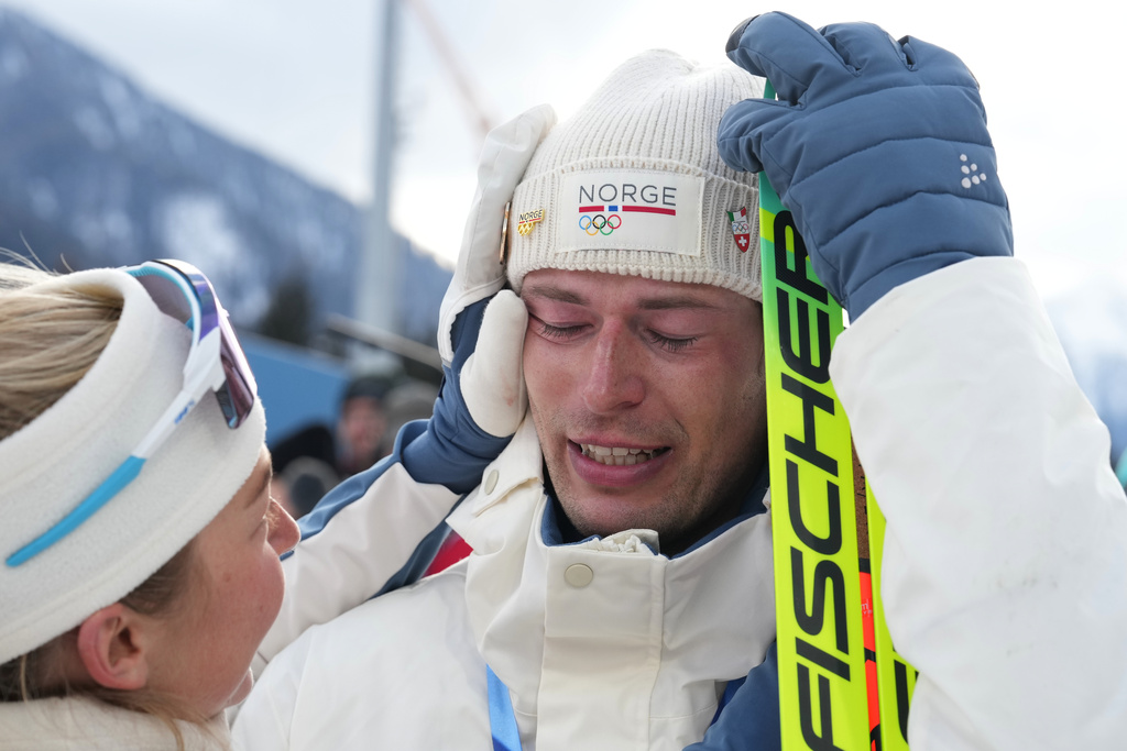 ADDS NAME OF TEAMMATE - Sturla Holm Laegreid, of Norway, reacts after he won bronze as teammate Ingrid Landmark Tandrevold comforts him after the men's 20-kilometer individual biathlon race at the 2026 Winter Olympics in Anterselva, Italy, Tuesday, Feb. 10, 2026. (AP Photo/Andrew Medichini)
