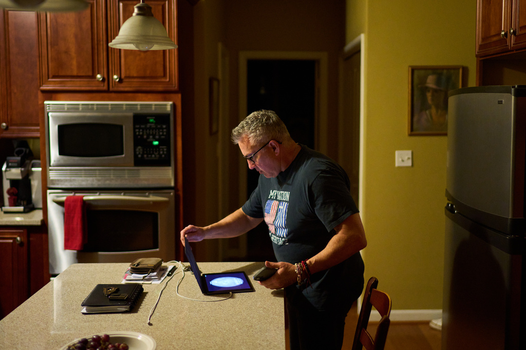 Chris Colocousis, whose retirement savings were stolen by a scammer, looks at his tablet at his home in Raynham, Mass., Tuesday, March 10, 2026. (AP Photo/David Goldman)