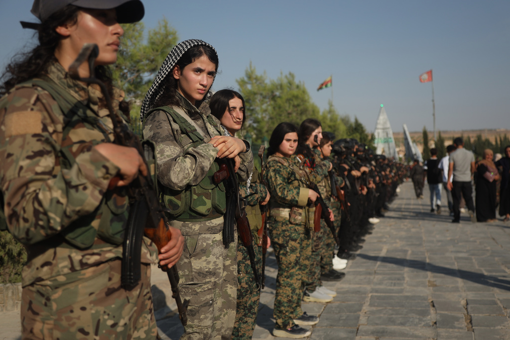 Fighters with the Kurdish Women's Protection Units, or YPJ, stand during a funeral ceremony for prisoners who died in a fire that broke out during unrest at the local prison following days of tensions and protests in the predominantly Kurdish city of Kobani, northern Syria, Monday, Sept. 14, 2026. (AP Photo/Baderkhan Ahmad)