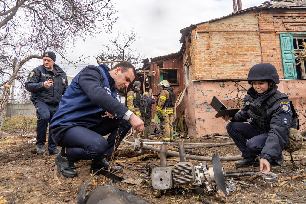 Police officers examine the fragments of a Russian drone that hit a private house during air attack in Kharkiv, Ukraine, Wednesday, March 25, 2026. (AP Photo/Andrii Marienko)