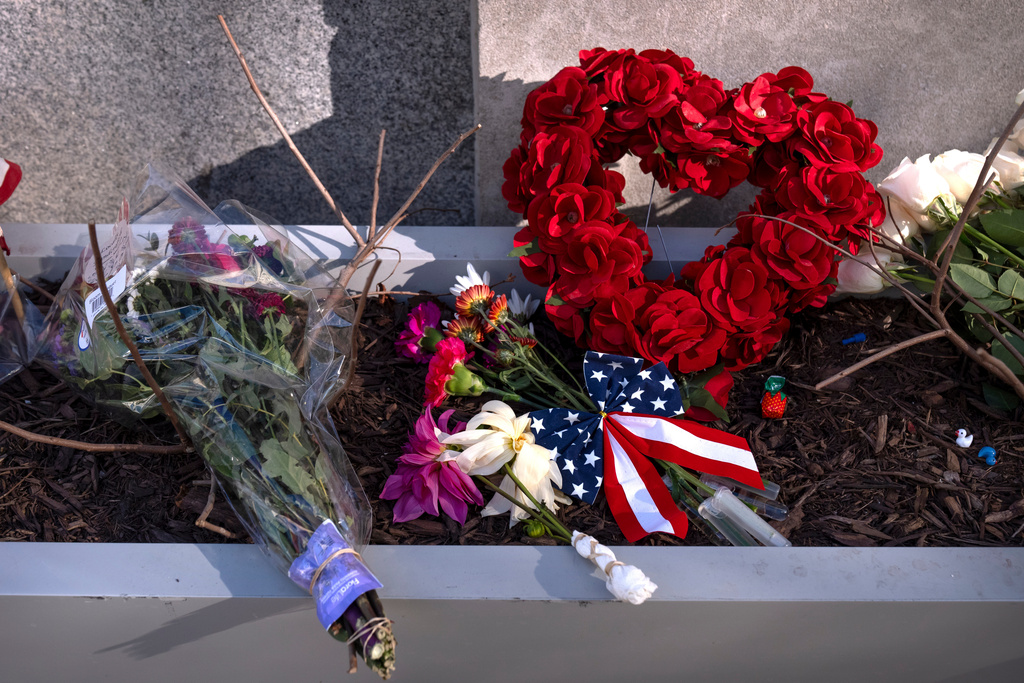 A small memorial of flags, flowers, other items are seen in a planter, Friday, Nov. 28, 2025, near the site where two National Guard members were shot in Washington. (AP Photo/Mark Schiefelbein)