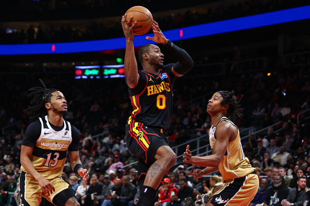 Atlanta Hawks forward Jonathan Kuminga (0) looks to pass against Washington Wizards guards Sharife Cooper (13) and Tre Johnson, right, during the first half of an NBA basketball game, Tuesday, Feb. 24, 2026, in Atlanta. (AP Photo/Colin Hubbard)