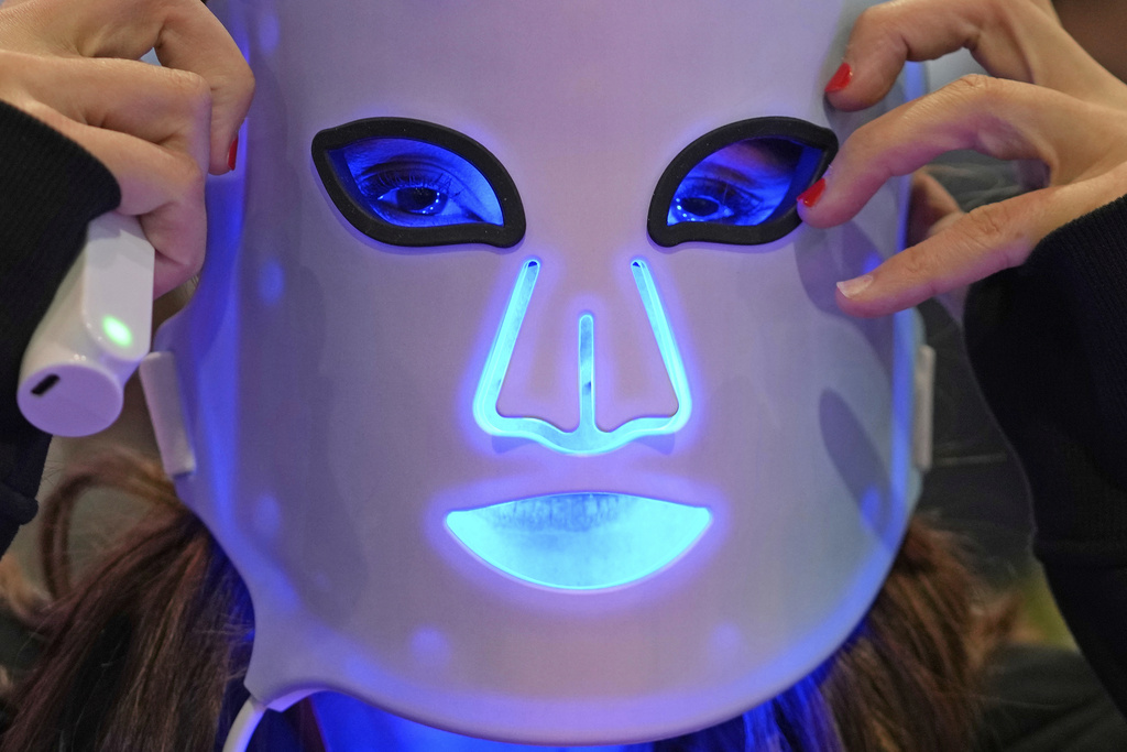 FILE - A representative for a light therapy mask company demonstrates one of the devices during the CES tech show in Las Vegas, on Friday, Jan. 6, 2023. (AP Photo/Rick Bowmer, File)