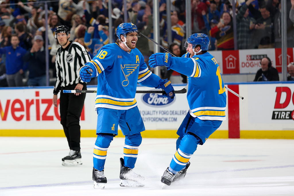 St. Louis Blues' Robert Thomas (18) celebrates with Cam Fowler (17) after scoring during the overtime period of an NHL hockey game against the Edmonton Oilers Friday, March 13, 2026, in St. Louis. (AP Photo/Scott Kane)