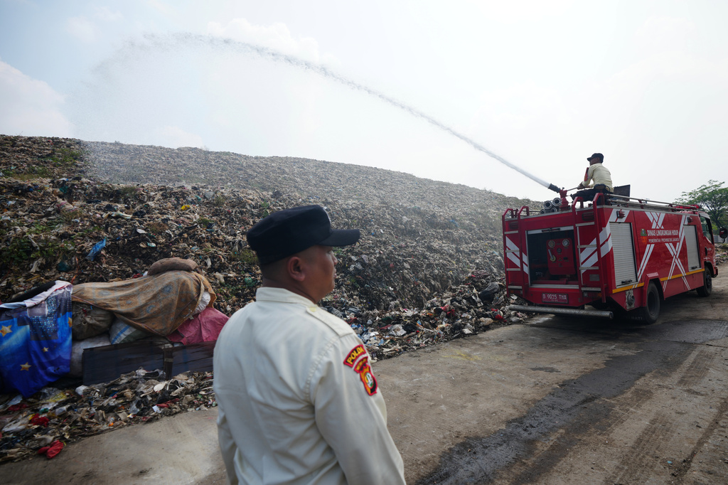 Workers spray water to cool a pile of garbage during hot weather at the Bantargebang landfill on the outskirts of Jakarta, Indonesia, Monday, July 6, 2026. (AP Photo/Tatan Syuflana)