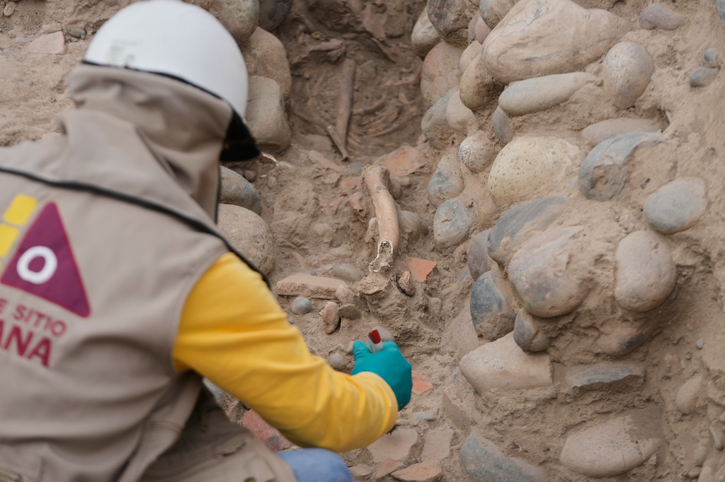 An archaeologist excavates skeletal remains at the Huaca Pucllana archaeological site in Lima, Peru, Tuesday, Aug. 18, 2026. The remains are from the Lima culture, according to the excavation's leader Gladys Paz. (AP Photo/Martin Mejia)
