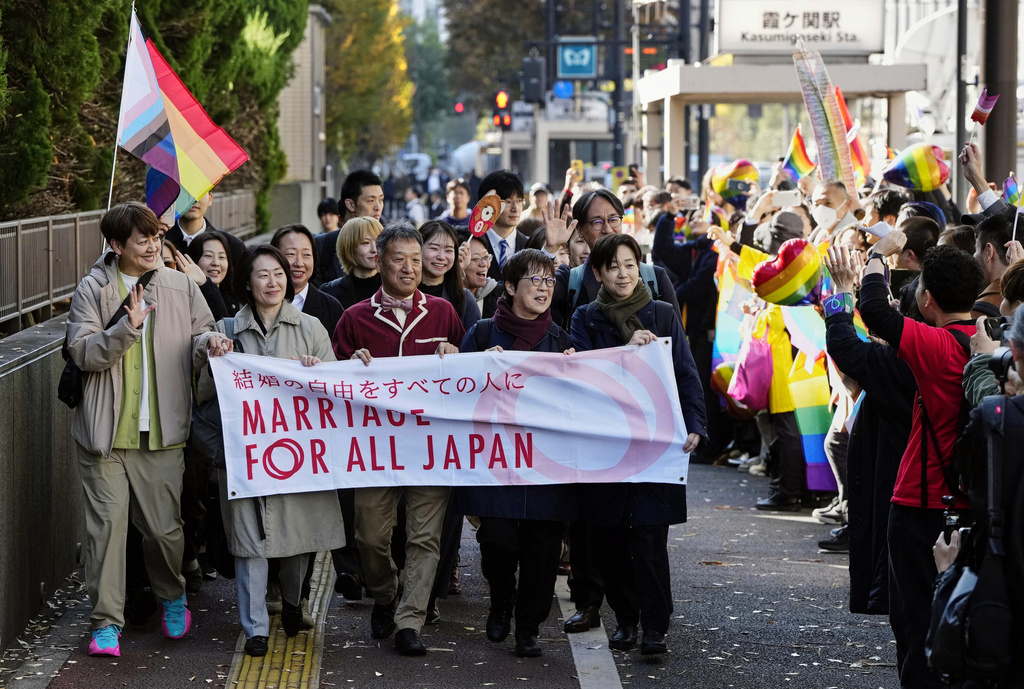 Plaintiffs of same-sex couples march towards a high court, walking along people gathering before its ruling on same-sex marriage in Tokyo, Friday, Nov. 28, 2025. (Miki Matsuzaki/Kyodo News via AP)