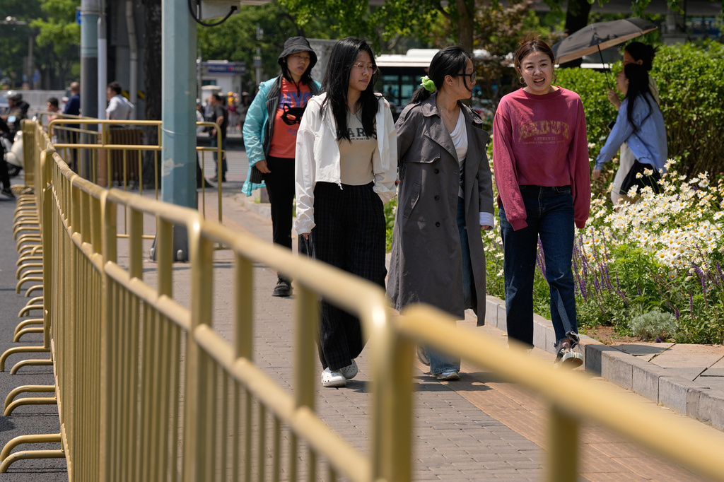Women walk along the barricades placed along the pedestrian walkway as security gets tighten ahead of U.S. President Donald Trump's visit, in Beijing, Tuesday, May 12, 2026. (AP Photo/Andy Wong)