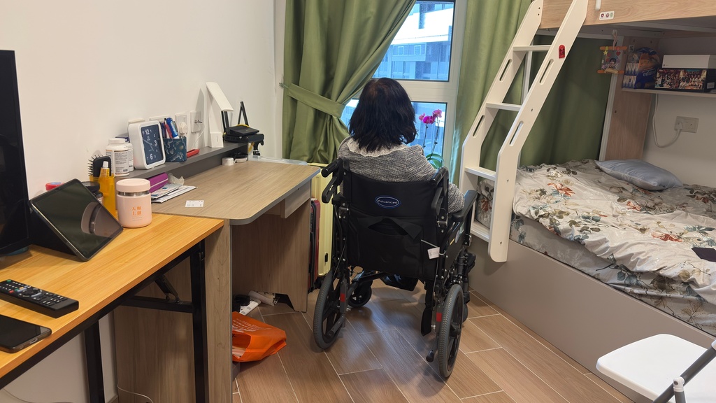 Kit Chan, a resident displaced by the Wang Fuk Court fire, poses for a photograph at her temporary housing unit at a youth hostel, on Saturday, Feb. 7, 2026. (AP Photo/Kanis Leung)