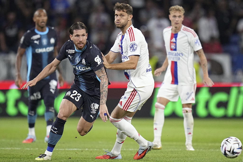 Marseille's Pierre-Emile Hojbjerg, left, challenges for the ball with Lyon's Francis Tessmann during the French League One soccer match between Lyon and Marseille, in Decines, outside Lyon, France, Sunday, Aug. 31, 2025. (AP Photo/Laurent Cipriani)