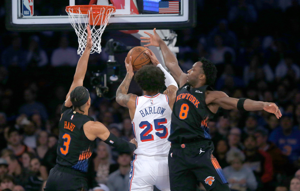 New York Knicks guard Josh Hart, left, and forward OG Anunoby, right, defend against Philadelphia 76ers forward Dominick Barlow, middle, during the first half of an NBA basketball game, Friday, Dec. 19, 2025, in New York. (AP Photo/John Munson)