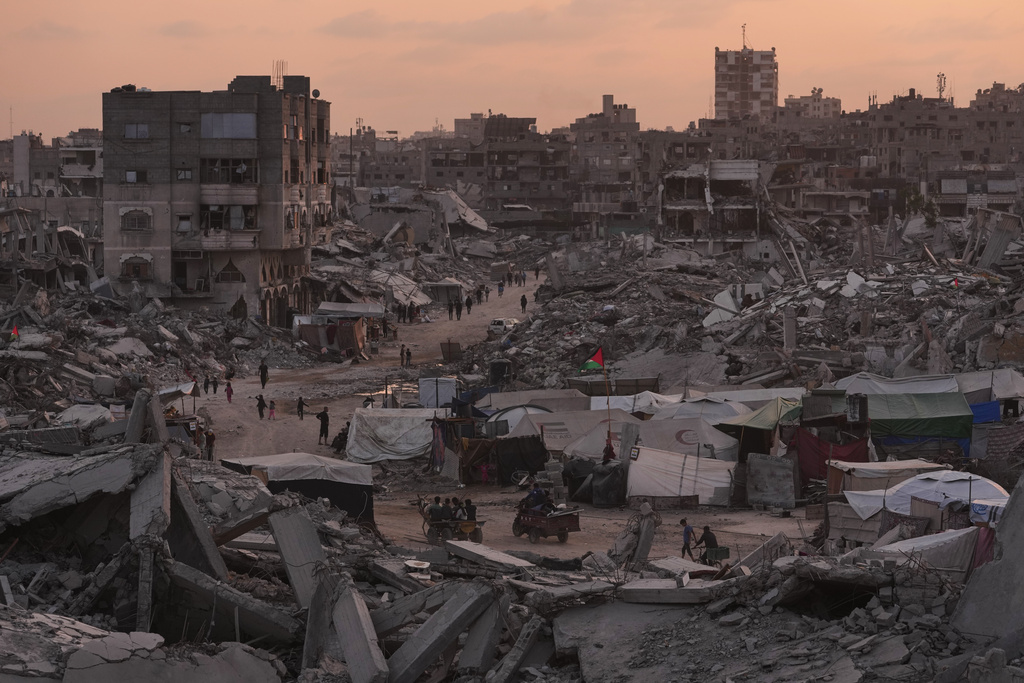 Palestinians walk through the destruction caused by the Israeli air and ground offensive in Sheikh Radwan neighborhood in Gaza City, Tuesday, Nov. 11, 2025. (AP Photo/Jehad Alshrafi)
