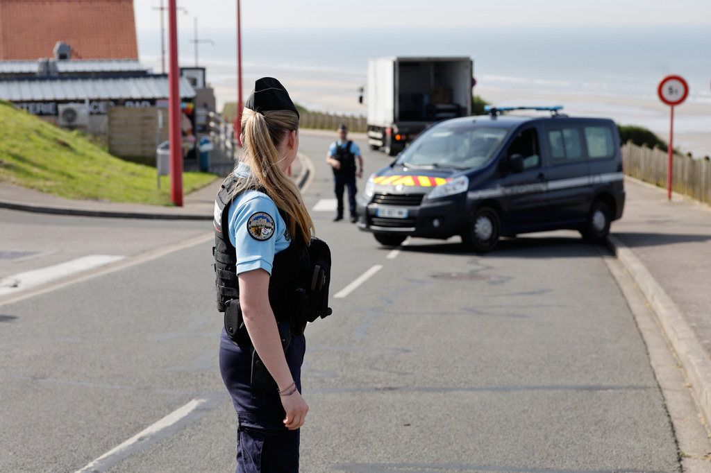 A police officer stands guard after a migrant taxi-boat accident, in Equihen-Plage, northern France. Thursday, April 9, 2026. (AP Photo/Jean-Francois Badias)