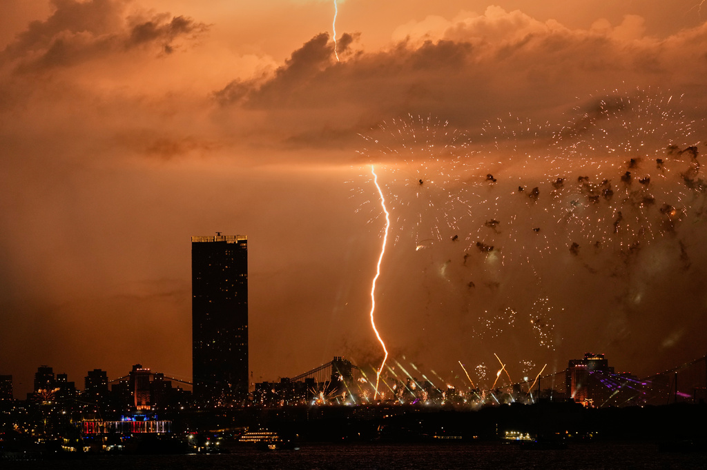 A bolt of lightning strikes as fireworks are set off of the Brooklyn Bridge, as seen from Bayonne, N.J., Saturday, July 4, 2026. (AP Photo/Seth Wenig)